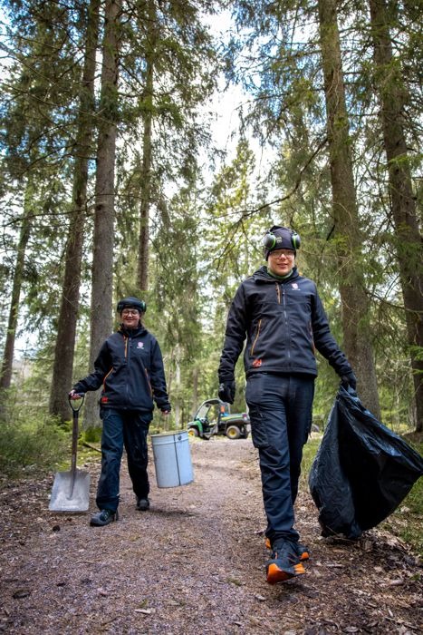 Två personer i daglig verksamhet arbetar utomhus.
